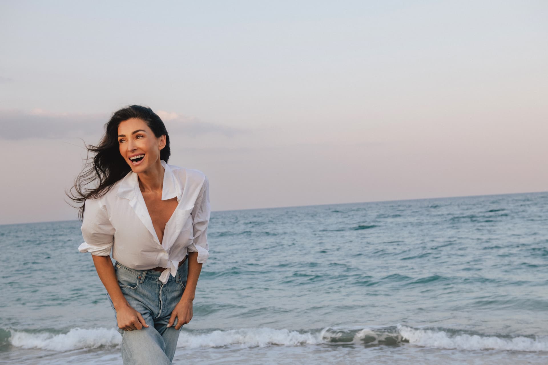 Founder standing on a beach with ocean waves and sky in the background
