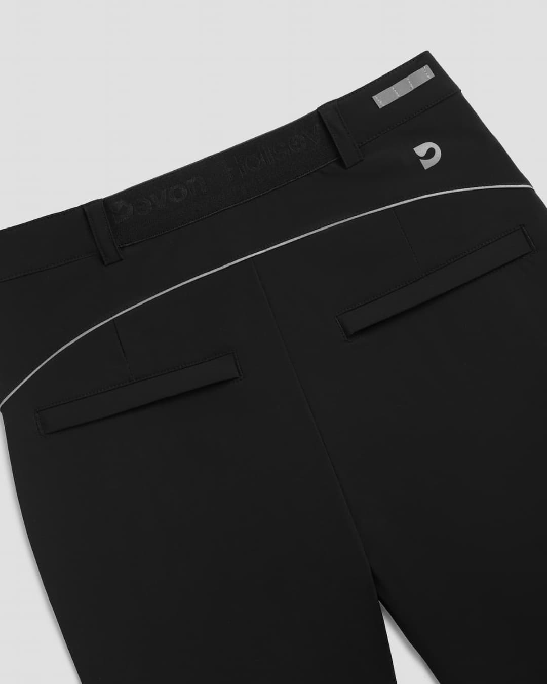 Close-up of black athletic leisure Inka pants with white stitching, zip pockets, a tee holder for golf.