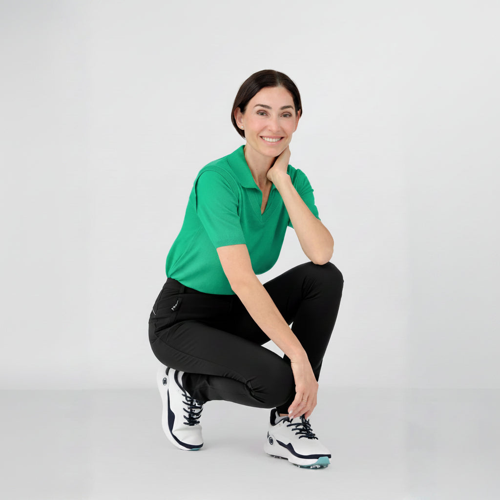 Woman wearing a cashmere green polo shirt and black athletic leisure Inka pants sitting