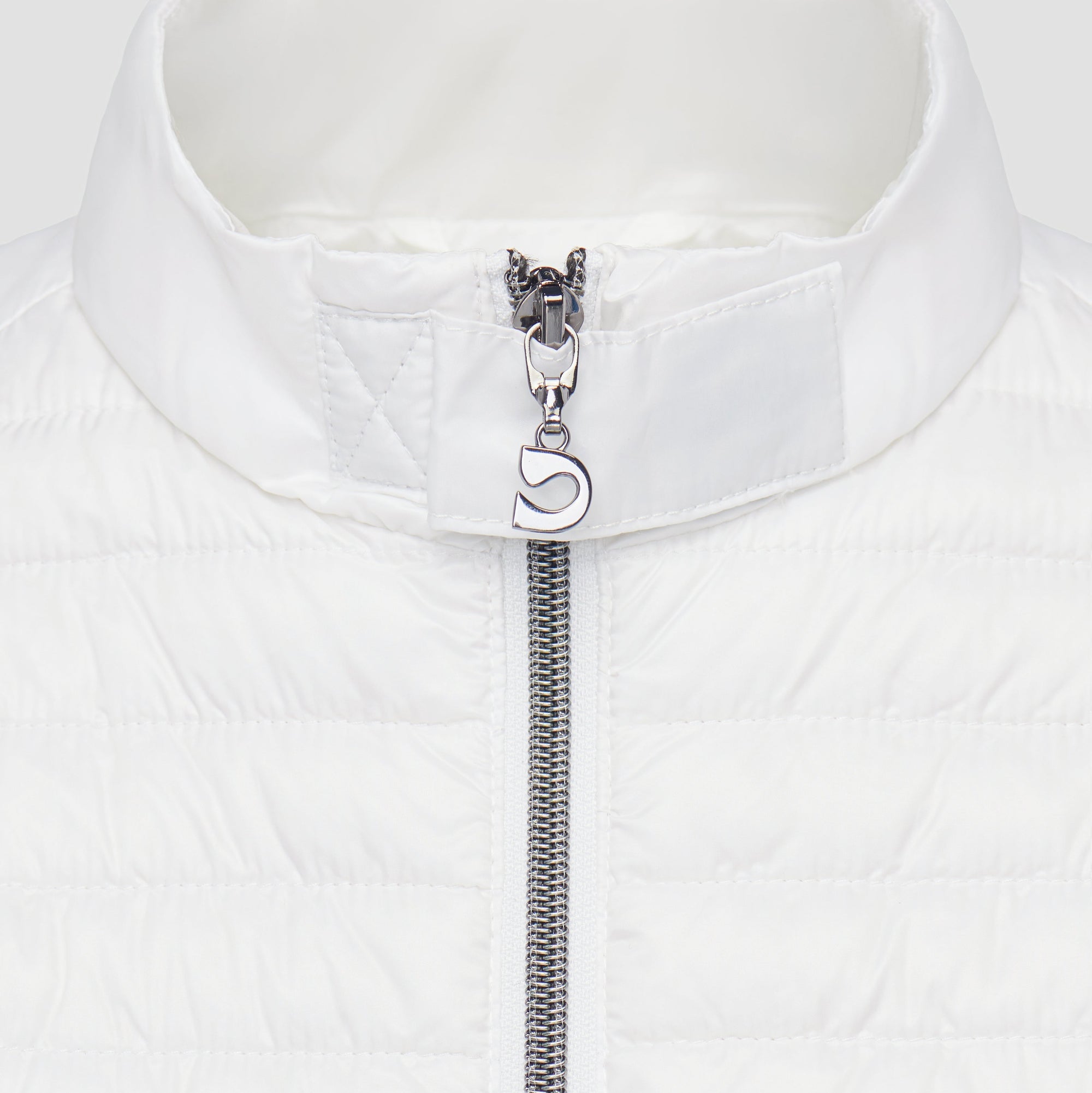 Close-up of a white moto jacket with a silver zipper and decorative pull tab on a white background