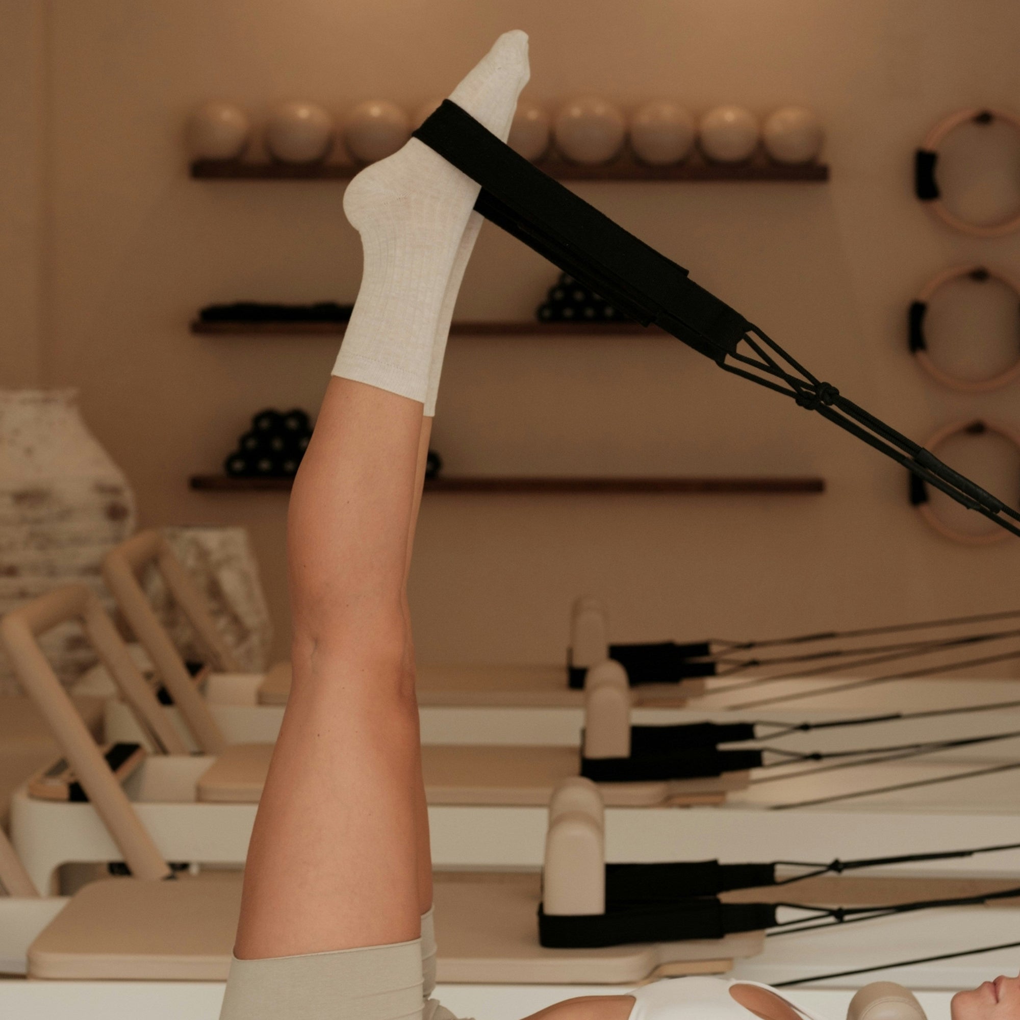 Person using a Pilates reformer machine in a studio setting